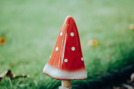 Decorative red fly mushroom in a white dot on a green lawn. Decor for home garden and homestead area. Figurine of poisonous mushrooms fungus outdoor.の写真素材