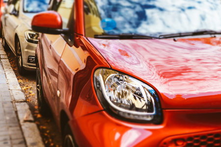 Red car headlight. Modern cars parked on an urban street. Bumper headlights close up. Electric automobile light. Traffic on the city street. Drivers.の写真素材