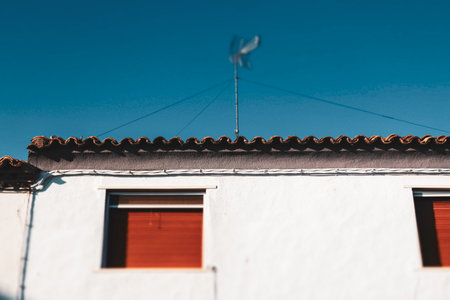 Mediterranean architecture. Old building residential facade, white house with red shutters in windows against blue sky. Minimalist cropped photo.の写真素材