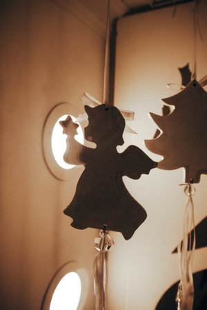 New Year's toy figure of an angel on a light vertical background. Christmas tree wooden toy. Cinematic vertical photo. Craft toys. New Year decor.の写真素材