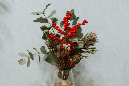 A beautiful Christmas or New Year's bouquet of Viburnum, Ilex and brunia berries in home interior. Flower arrangement, floristics and floral decor.の写真素材