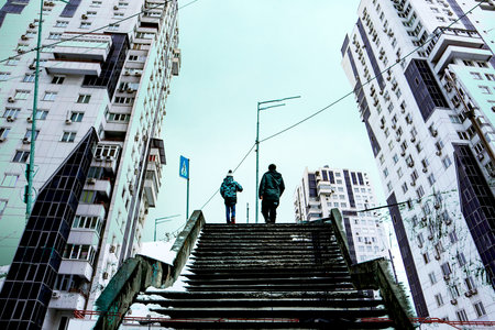 High-rise modern houses in a metropolis in winter. Stone staircase leads upward, two people on the horizon. Urban scene. Tall buildings low angle viewの写真素材