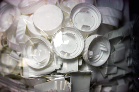 A close-up view of a collection of white bottle caps in a plastic container, plastic parts. White bottle caps, revealing details of the plastic.の写真素材
