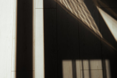 Sunlight creates geometric shadows on a wooden floor, forming abstract pattern. Abstract image...