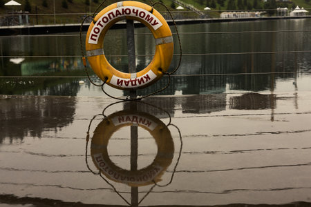 A reflective shot captures a life preserver in a lakeside scene, with its reflection mirroring the scene.の写真素材
