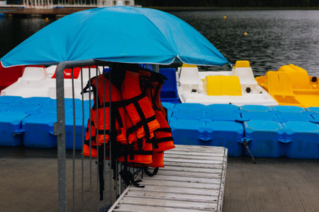 Colorful pedal boats, safety gear and a blue umbrella provide water fun at the lakeside resort. Life...
