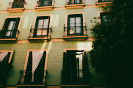 An inviting shot of a green building exterior showcasing its balconies and windows. The building has a green facade and is partially obscured by treesの写真素材