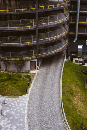 A modern parking garage with a winding cobblestone ramp and a few levels. A multi-story parking exterior with a descending cobblestone ramp from aboveの写真素材