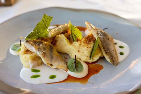Delicate fish fillets are artistically arranged with mashed potatoes and a flavorful sauce on a...