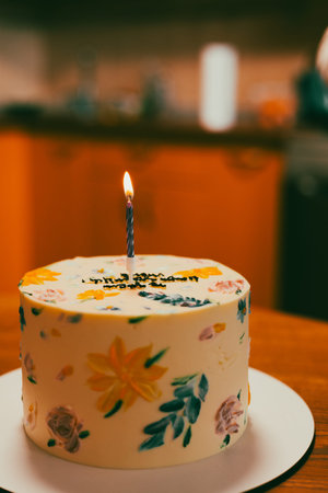 A beautifully decorated cake with a lit candle, perfect for a special birthday celebration. A...