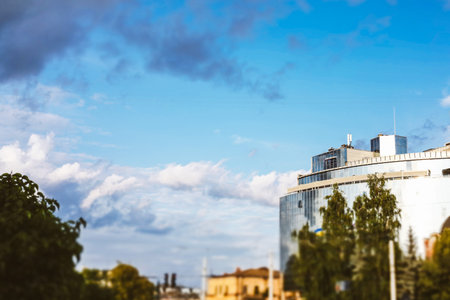 The modern building with a glass facade stands under a blue sky with soft clouds. A modern building...