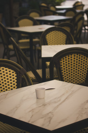 An inviting outdoor cafe setting with empty tables and chairs. A serene outdoor cafe scene with...