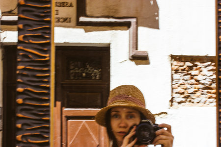 A tourist woman in a straw hat captures a moment with her camera in a mirror. A photographer girl...
