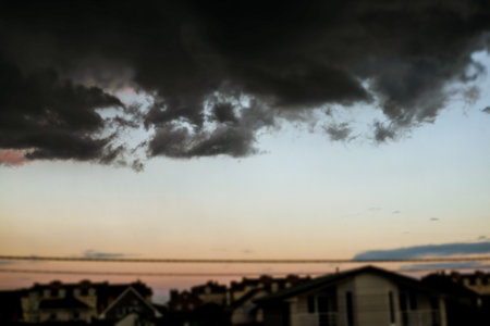 Storm clouds gather over a suburban neighborhood at sunset, creating a dramatic scene. Dramatic sky with dark storm clouds gathering over a residential area. A beautiful, yet ominous, weather scene.の写真素材