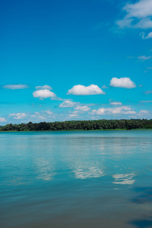 A beautiful, scenic lake scene with bright blue sky and fluffy clouds. A scenic shot of a tranquil...