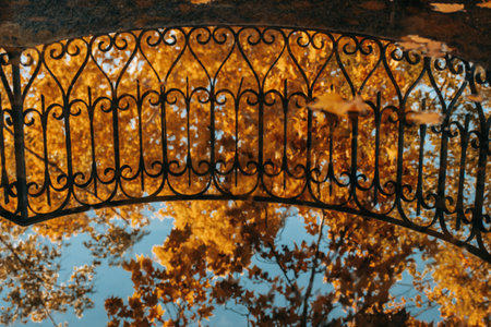 Ornamental wrought iron railing frames a vibrant autumnal scene filled with yellow and orange...