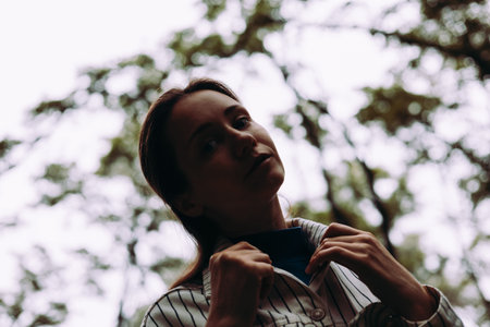A beautiful woman in the forest, looking with a soft and dreamy feel. A girl gazes up, pulling at...