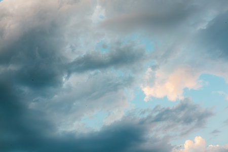 Summer sky is filled with fluffy clouds in varying shades of blue, gray, white. Dramatic clouds fill...