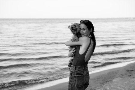Tender portrait of a young woman hugging a small Yorkshire terrier dog. Authentic emotional moment showing love, care, friendship and human animal bond. Perfect for lifestyle and pet themes Cute doggyの写真素材