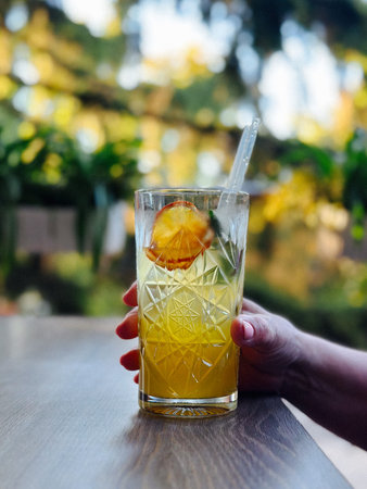 Refreshing summer drink with orange slice and mint in a crystal glass. Trendy outdoor lifestyle...