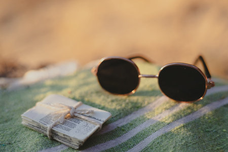 Round sunglasses and old papers arranged on striped green fabric. A pair of round sunglasses rests...