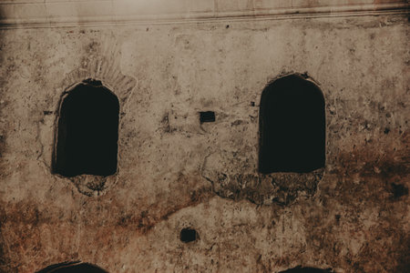Old wall with arched openings A weathered wall with two arched openings and a dark interior. The textures and colors create a vintage aesthetic.の写真素材