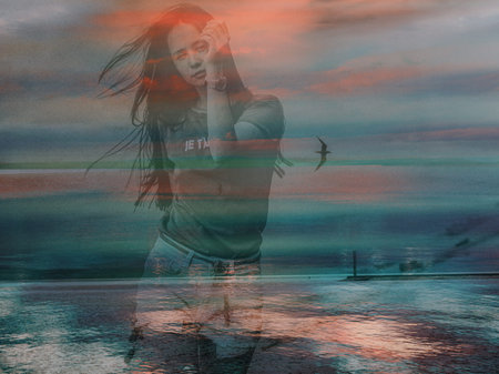 Woman by the sea at sunset with a bird flying in the sky. A woman walking near the ocean, a bird...
