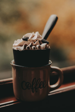 Delicious coffee dessert with whipped cream and coffee beans in a mug. A delightful coffee-flavored dessert is topped with whipped cream and coffee beans, served in a charming mug.の写真素材
