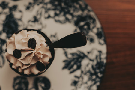 Delicious coffee dessert with chocolate spoon on a floral patterned plate. This overhead shot captures a delightful dessert featuring coffee beans and a chocolate spoon.の写真素材