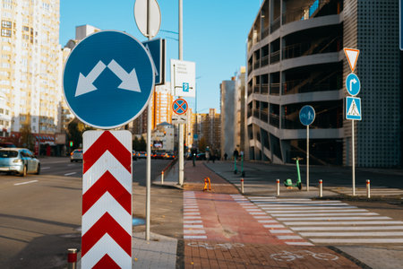Road signs indicating directions and warnings in an urban environment. A street scene with various road signs, including a bicycle lane and pedestrian crossing, under a clear blue sky.の写真素材