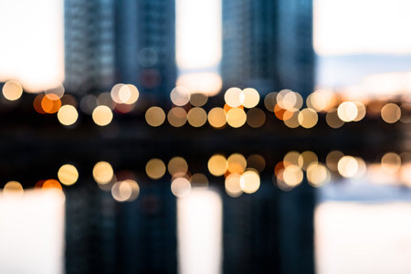 Abstract cityscape with soft bokeh lights reflecting on water at dusk. Modern urban mood, minimalism, night city atmosphere, dreamy blue tones, contemporary aesthetic, creative background concept.の写真素材