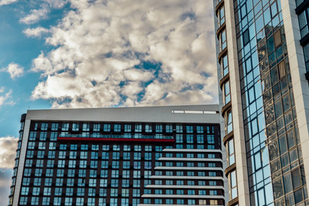 KYIV, Ukraine 4 October 2025 Modern architecture of a high-rise building against a cloudy blue sky. The buildings glass facade reflects the sky, creating a striking contrast with the clouds above.のeditorial素材