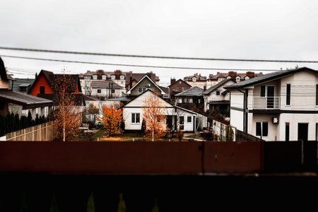 KYIV, Ukraine 12 November 2025 Residential neighborhood with houses and autumnal trees on a cloudy day. A view of suburban cottages roofs under a skyのeditorial素材
