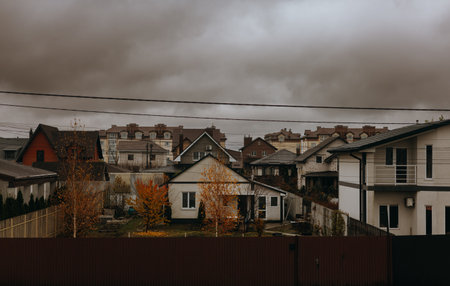 KYIV, Ukraine 12 November 2025 Residential neighborhood with houses and autumnal trees on a cloudy day. A view of suburban cottages roofs under a sky.のeditorial素材