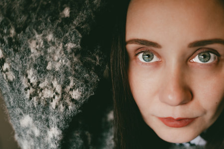 Close-up portrait of a young woman with natural makeup, soft lighting, warm tones. Intimate mood, focus on blue eyes and skin texture, red lips. Cozy, emotional, and artistic female beauty and smile.の写真素材