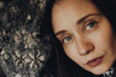 Close-up portrait of a young woman with natural makeup, soft lighting, warm tones. Intimate mood, focus on blue eyes and skin texture, red lips. Cozy, emotional, and artistic female beauty and smile.の写真素材