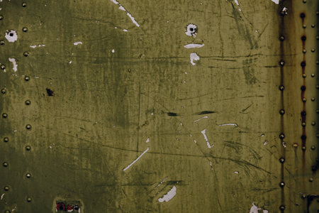 An old weathered metal surface with peeling paint, rust stains, scratches, textures. Grunge detail ideal for backgrounds, design elements, vintage industrial concepts. Metallic surface and rivets.の写真素材