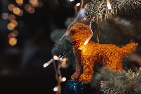 Cozy Christmas tree ornament with a handmade plush dog, glowing fairy lights and warm festive bokeh. Perfect for New Year 2026 ambience, holiday decor concepts, seasonal celebration design projects.の写真素材