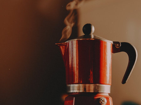 The essence of a cozy morning with this vibrant, steaming red moka pot. Perfect for illustrating home coffee brewing, authentic Italian espresso culture, and a warm, inviting lifestyle aesthetic.の写真素材