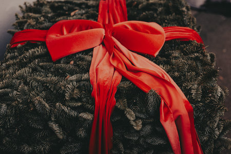 Christmas wreath crafted from deep green fir branches, accented with a large, elegant red velvet...
