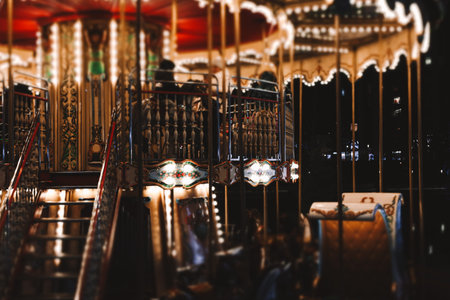 KYIV, Ukraine 20 December 2025 Vintage carousel glowing at night with warm lights, ornate details in a city park. Festive winter holiday atmosphere.