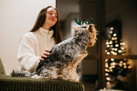 Festive Christmas moment at home - a young white woman sharing a cozy, joyful evening with a small...