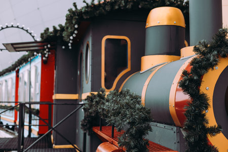 Decorative Christmas steam train decorated with pine garlands and lights at a holiday market....