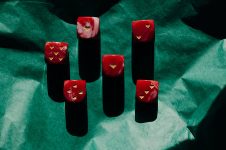 Red marble dice with gold heart pips on green crumpled paper. Romantic gambling concept, Valentine's...