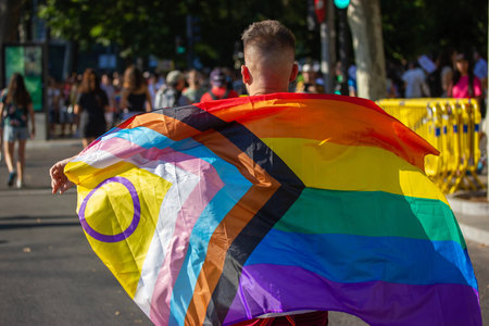 MADRID, SPAIN - JULY 02, 2024 Back view of a person draped in an intersex-inclusive Progress Pride...