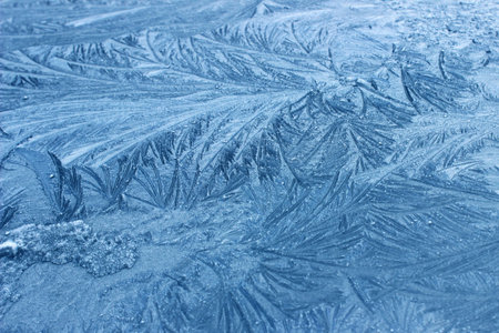 Frost patterns on a frozen window in winter, closeup of photo