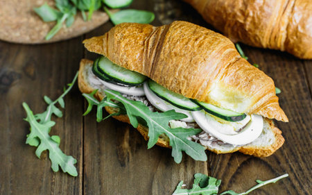 Croissant with tuna, egg, cucumber and arugula on wooden backgroundの写真素材