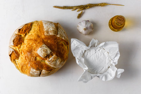 Ingredients for making baked camembert cheese in bread. Camembert cheese, fresh round wheat bread,...