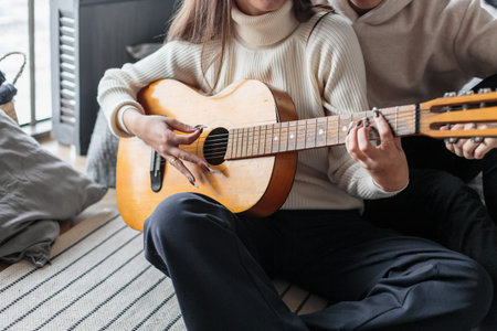 Young woman playing guitar. Close-up of woman hands playing classic guitar. teenager learning...
