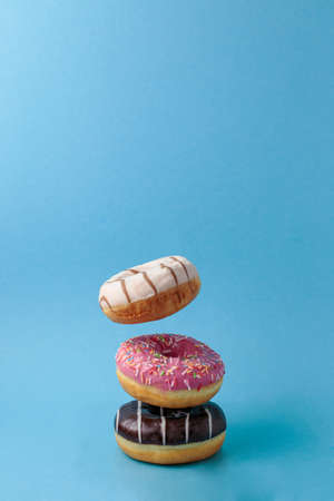 Flying levitating multicolored donuts on a blue background.の写真素材